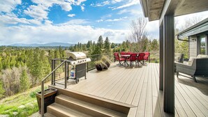 A deck with outdoor furniture, a grill, and a view of a forested landscape. - Mtn-View Retreat w/ Fire Pits & Grill in McCall! (McCall)