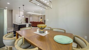 Un espace repas comprenant une table en bois, des chaises, un vase central et des luminaires suspendus.