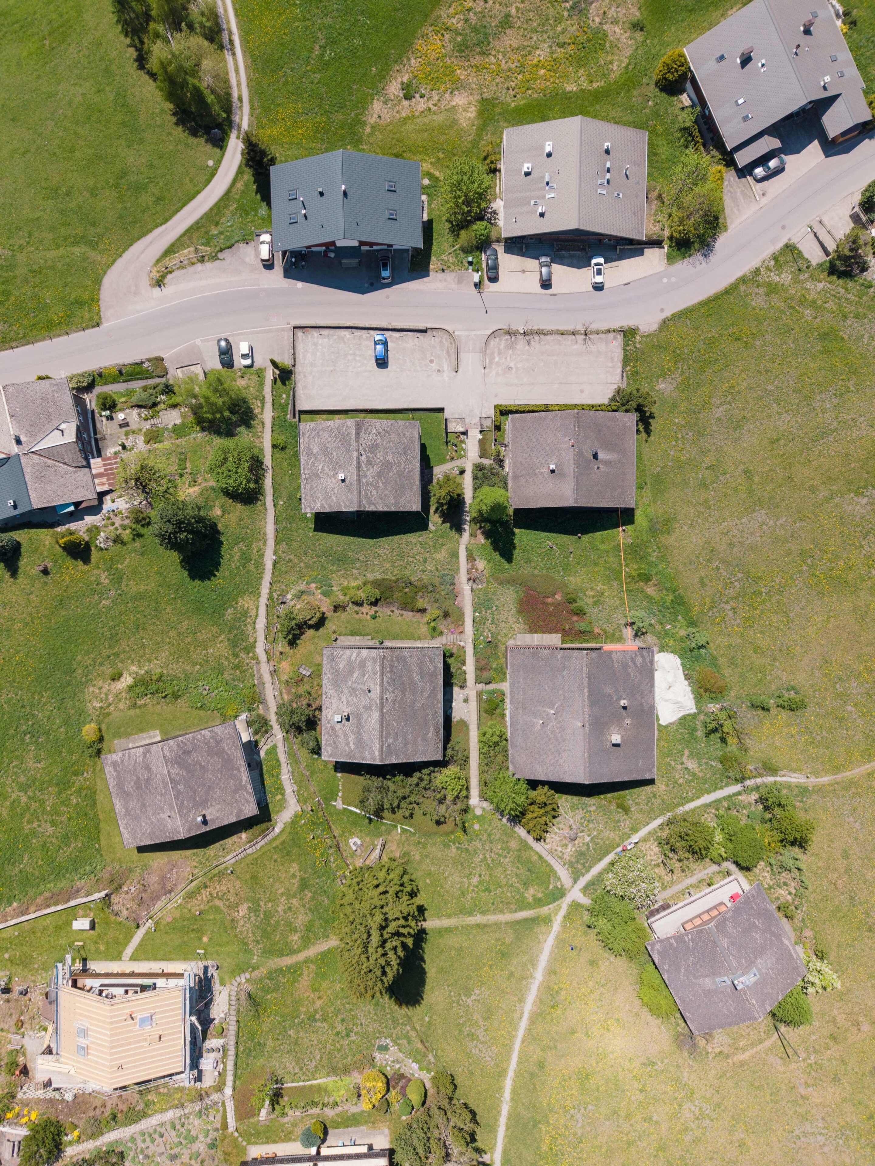 Vista aérea de una zona residencial con varias casas, una calle y un edificio pequeño.