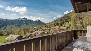 A balcony with a view of a mountain village, wooden railings, and a table. - Mountain View Apartment in Grindelwald (Grindelwald)
