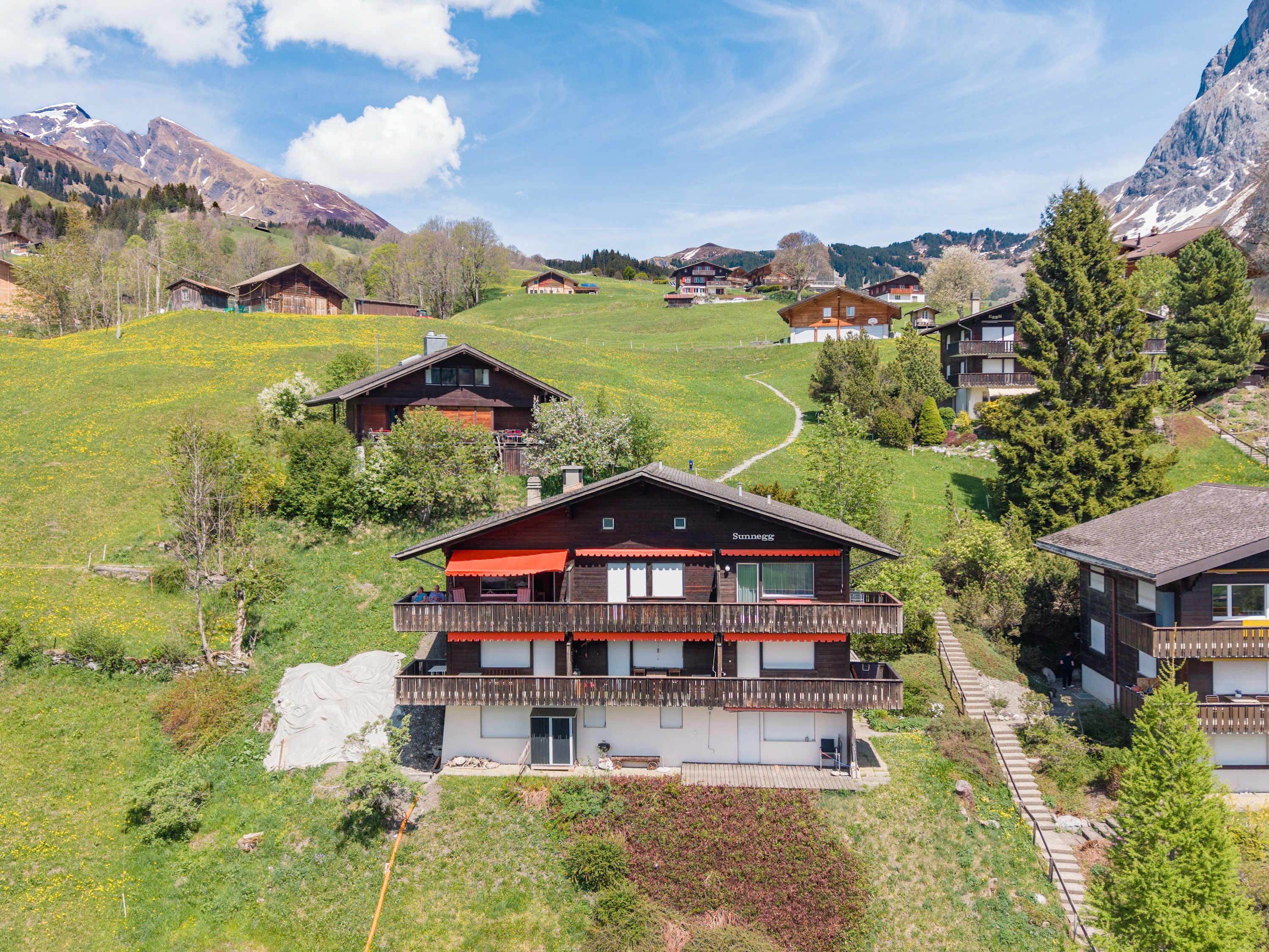 Un village de montagne aux maisons en bois, avec un bâtiment remarquable à toit rouge et un ciel dégagé.