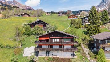 Un village de montagne aux maisons en bois, avec un bâtiment remarquable à toit rouge et un ciel dégagé.