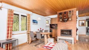 A cozy living area with a fireplace, wooden furniture, and a dining table. - Mountain View Apartment in Grindelwald (Grindelwald)