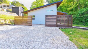 A modern single-story building with a sloped roof, a gravel driveway, and a wooden fence. - Appalachian Cabin Haven! Gateway to Lake Linville! (Mt Vernon)