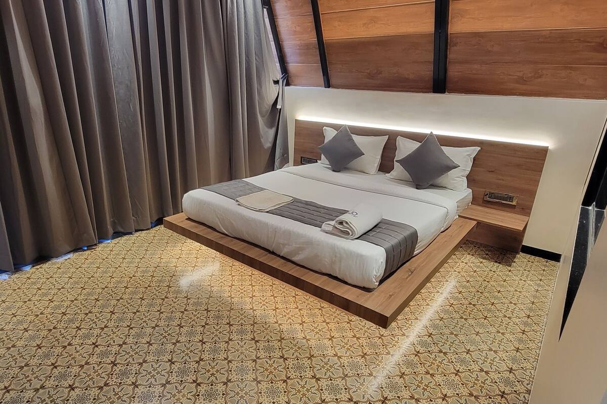 Un dormitorio moderno con cabecera de madera, alfombra estampada y una cama grande con almohadas.