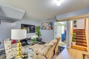 A living room with a sofa, a coffee table, a TV, a painting, and a staircase. - Walkable Base Near Dtwn, Penn Station & MetLife (Newark)