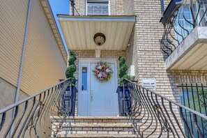 A building entrance with a white door, a security camera sign, and a decorative wreath. - Walkable Base Near Dtwn, Penn Station & MetLife (Newark)