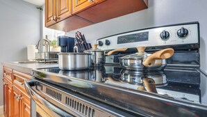 Una cucina con mobili in legno, un fornello in acciaio inox e una pentola sul piano di lavoro.