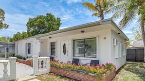 A single-story house with a white exterior, a brick flower bed, and a small porch with chairs. - 4 Mi to Surfside Beach! North Miami Apt (North Miami)