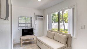 A room with a sofa, TV, and window overlooking greenery. - 4 Mi to Surfside Beach! North Miami Apt (North Miami)