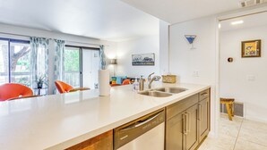 Een moderne keuken met een vaatwasser, een spoelbak en een eethoek met stoelen.
