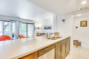 Eine moderne Küche mit Geschirrspüler, Spüle und Essbereich mit Stühlen.