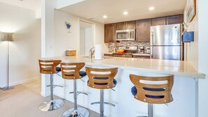 Een moderne keuken met houten barstoelen, roestvrijstalen apparatuur en een groot keukenblok.