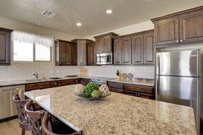 A kitchen with granite countertops, stainless steel appliances, and wooden cabinets. - Golf, Gamble & Get Away! Mesquite Desert Retreat (Mesquite)