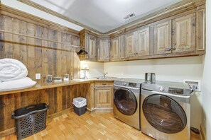 A laundry room with wooden cabinets, a washing machine, a dryer, a sink, and a trash bin. - Franklin Cabin w/ Hot Tub, Theater & Fire Pit! (Franklin)