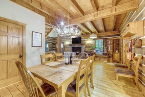 A wooden interior with a dining table, chairs, a fireplace, and a television. - Franklin Cabin w/ Hot Tub, Theater & Fire Pit! (Franklin)