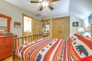 A bedroom with a wooden bed, a dresser, a ceiling fan, and a door leading to another room. - Franklin Cabin w/ Hot Tub, Theater & Fire Pit! (Franklin)