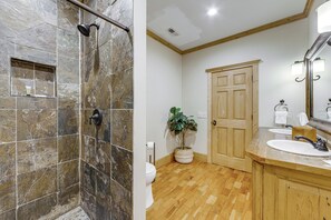A bathroom with a shower, toilet, sink, and wooden cabinets. - Franklin Cabin w/ Hot Tub, Theater & Fire Pit! (Franklin)