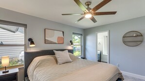 A bedroom with a bed, a ceiling fan, a window, a nightstand, a lamp, a wall-mounted shelf, and a framed picture. - Pet-Friendly Yard w/ Hot Tub! Peaceful Austin Home (Austin)