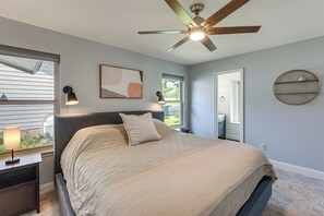 A bedroom with a bed, a ceiling fan, a window, a nightstand, a lamp, a wall-mounted shelf, and a framed picture. - Pet-Friendly Yard w/ Hot Tub! Peaceful Austin Home (Austin)