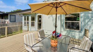 A glass-top table with a beige umbrella, striped chairs, and a potted plant. - Pet-Friendly Yard w/ Hot Tub! Peaceful Austin Home (Austin)