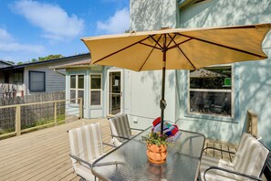 A glass-top table with a beige umbrella, striped chairs, and a potted plant. - Pet-Friendly Yard w/ Hot Tub! Peaceful Austin Home (Austin)