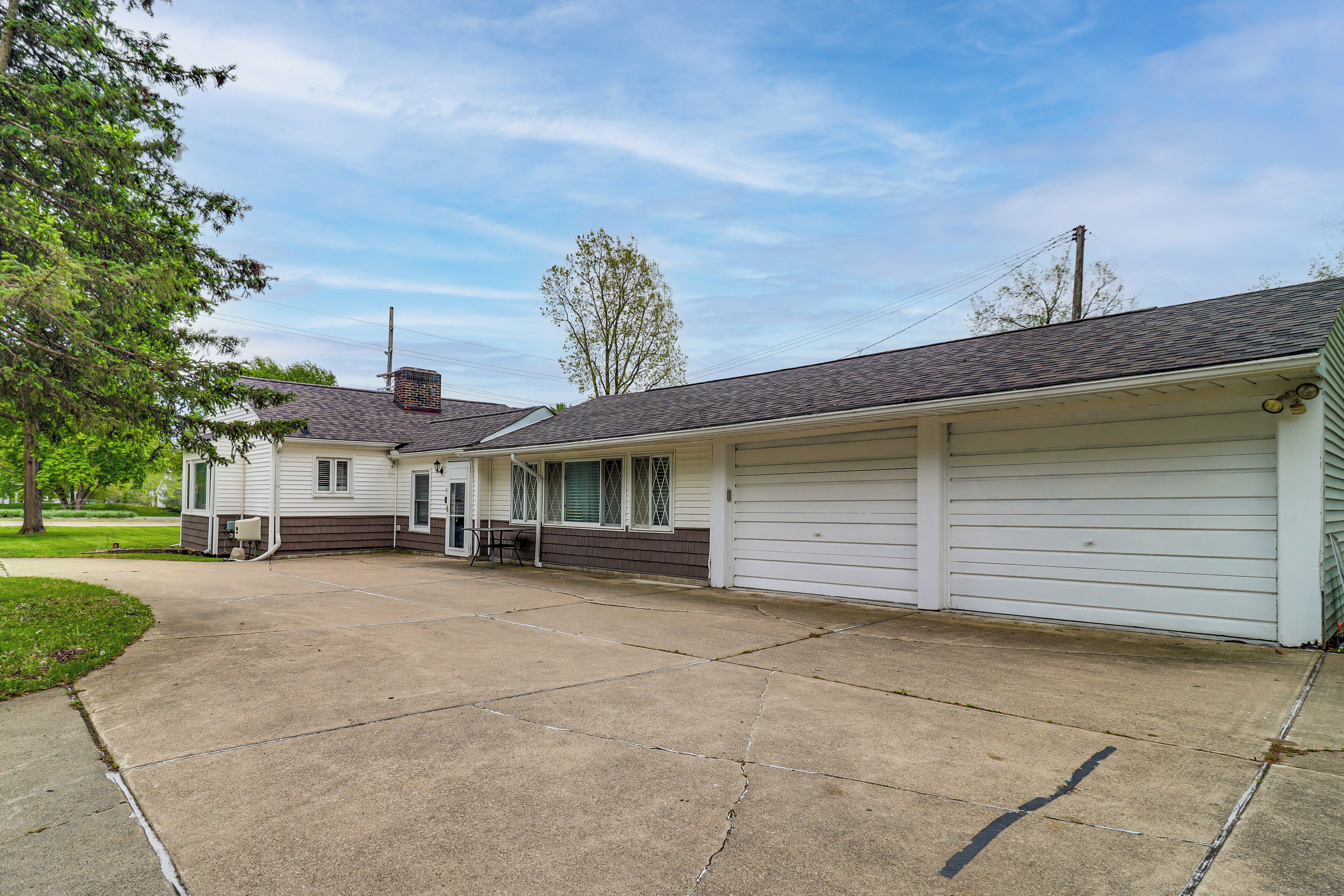 A two-story building with a garage, a covered porch, and a driveway.