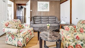 Une pièce comprenant un canapé, deux fauteuils, une table basse en marbre et un tableau encadré accroché au mur.