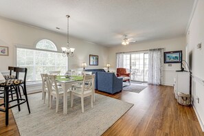 A dining area with a table and chairs, a blue sofa, and a ceiling fan. - Pool Access! Myrtlewood Villas Golf Escape (Myrtle Beach)