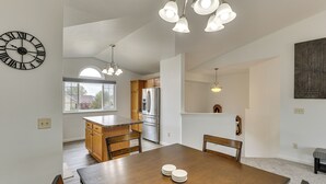 Une cuisine moderne avec des meubles en bois, un réfrigérateur en acier inoxydable et un coin repas comprenant une table et des chaises en bois.