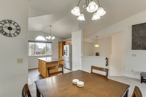 Une cuisine moderne avec des meubles en bois, un réfrigérateur en acier inoxydable et un coin repas comprenant une table et des chaises en bois.
