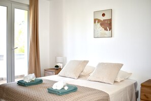 Een hotelkamer met een bed, nachtkastje, lamp en raam met gordijnen.