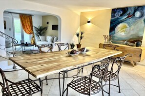 Een eethoek met een houten tafel, metalen stoelen en een schilderij aan de muur.