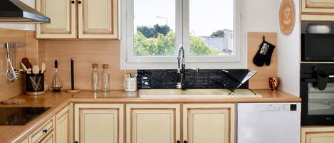 Une cuisine avec des meubles en bois, un lave-vaisselle et une fenêtre donnant sur un espace verdoyant.