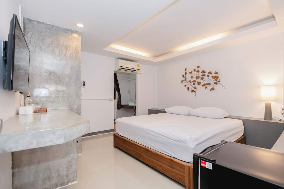 A modern bedroom with a bed, bedside table, and a mounted TV.