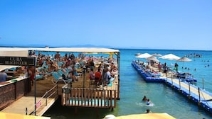 A beach club with a pool area, lounge chairs, and umbrellas. - Sultans And Kings Hotel (Didim)