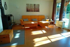 A living room with a sofa, a coffee table, a fireplace, and a window with curtains.