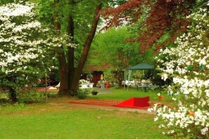Ein Garten mit Bäumen, einem Pavillon und Sitzgelegenheiten im Freien.