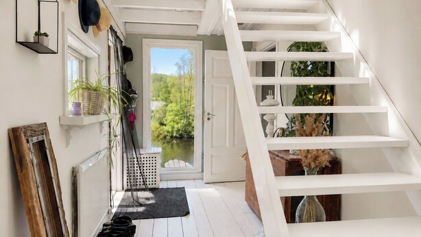 Una escalera blanca que lleva a una puerta con vistas a espacios verdes.