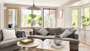 Una sala de estar moderna con un sofá gris, una mesa de centro redonda y una lámpara colgante.