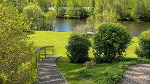 Un sendero a la orilla del río que lleva a un muelle, rodeado de exuberante vegetación y árboles.