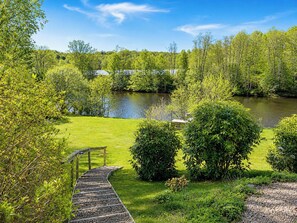 A riverside pathway leading to a dock, surrounded by lush greenery and trees. - Knäredsdrömmen by Interhome (Halmstad)