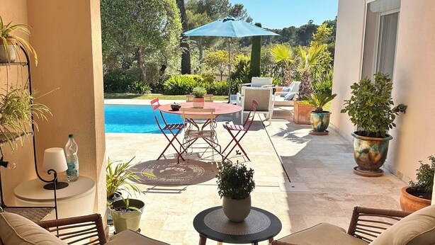 Une terrasse extérieure avec des meubles en osier, une piscine et des plantes en pot.