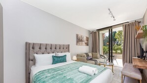 Ett hotellrum med en stor säng, en soffa, ett litet bord och utsikt över omgivningarna.