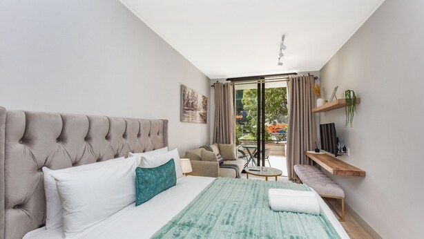 Ett modernt hotellrum med en stor säng, en soffa, ett litet bord och en balkong med utsikt.