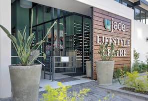 Ein moderner Gebäudeeingang mit einem Schild, auf dem 'the jade LIFESTYLE CENTRE' steht.