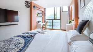 A bedroom with a bed, a TV, a clock, a window, and a desk area. - Summer Inn Sanya (Sanya)
