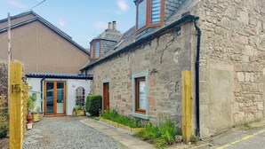 A stone building with a traditional design, featuring a small garden and a dog. - 3 bedroom accommodation in Nairn (Nairn)