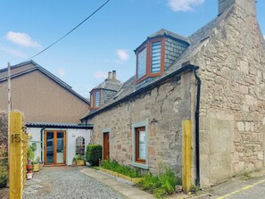 A stone building with a traditional design, featuring a small garden and a dog. - 3 bedroom accommodation in Nairn (Nairn)