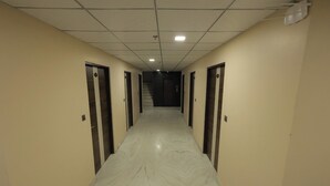 Un couloir doté d’un sol en marbre, de murs de couleur beige et de portes de part et d’autre.